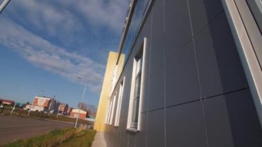 Modern office building with grey tiled facade and windows on city street close low angle shot. Architectural project