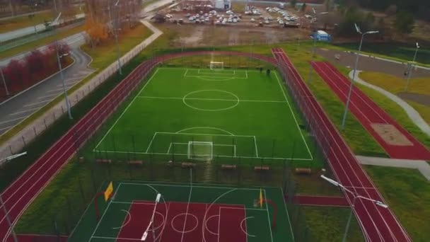 近代的なスポーツグラウンドの空中ビューに緑の芝生と大規模なサッカー場 チームボールゲームのトレーニングのための都市裁判所 — ストック動画