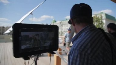 ALMATY, KAZAKHSTAN - JULY 27 2022: Film director watches video on camera monitor controlling shooting at set closeup. Filmmaking industry technology on July 27 in Almaty