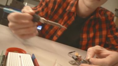 Man solders microchip repairing broken device at table in workshop closeup. Person assembles gadget at workplace
