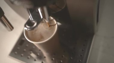 Woman grabs out cup with coffee from machine and spills drink on table close upper view. Messy beverage preparation