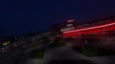 Stylish park and athletic arena building with neon decoration in evening city first point view. Urban lifestyle