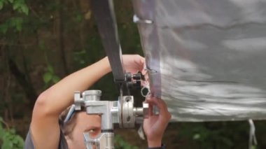 ALMATY, KAZAKHSTAN - JULY 19 2022: Crew adjusts silver sunlight reflector on filming set in yard. Filming staff prepares set for shooting scenes for upcoming movie on July 19 in Almaty