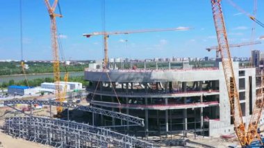 Mavi gökyüzünün altındaki modern şehir stadyumunun inşaat sahasında vinçler. Arena hava manzarasının beton temeli yakınındaki metal yapılar
