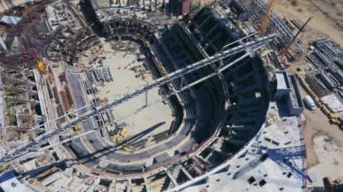 Turna yelkeni güneşli bir günde şehir spor sahasının üstünde çalışır. İnşaat alanının hava manzarasında stadyum beton temeli inşaatı