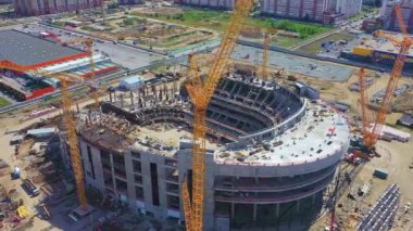 Oyunlar ve yarışmalar için spor salonu inşa etmek. Güneşli bir günde şehrin yakınındaki inşaat alanında büyük vinçler çalışıyor.