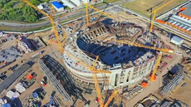 İnşaat vinçleri güneşli bir günde tribünlerle stadyum kasesinin beton yapılarına tırmanıyor. Arena, hava manzarası oluşturma sürecinde