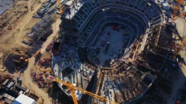 Stadyum beton temeli güneşli bir günde inşaat aşamasında. Vinçler ve makineler modern şehir hava manzarası inşa ediyor