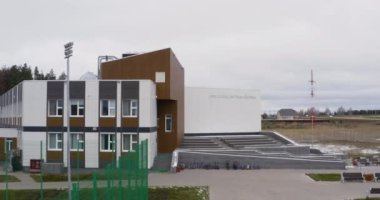 ALMATY, KAZAKHSTAN - OCTOBER 20 2022: Private school with empty yard and football stadium for students. Modern school territory with students bikes against grey sky on October 20 in Almaty