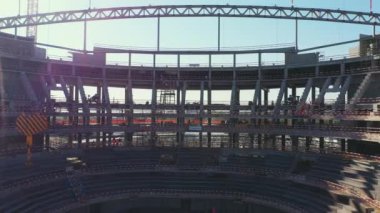 Construction of large arena by hired team of professional builders. Detailed process of football arena building in busy city