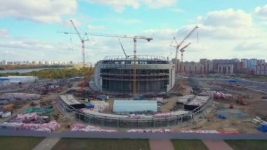 Yellow construction tower cranes near new football stadium near nice town. Professional company with equipment and machinery aerial view