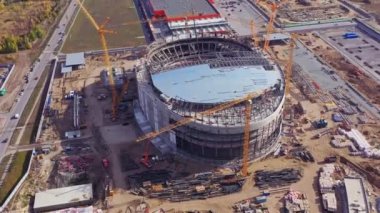 İnşaat alanında sarı vinçlerle donatılmış arena kasesi. Profesyonel takım hava manzaralı spor stadyumu inşaatı