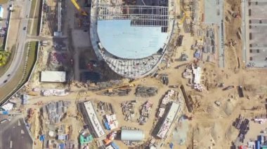 New constructed arena bowl at busy building site near busy highway. Process of building football stadium by yellow construction cranes