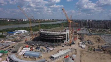 Arena kasesi inşaatı için vinçler hazır. Şehir havası manzarası yakınındaki nehir kıyısında futbol stadyumu inşa eden vinçler inşa ediliyor.