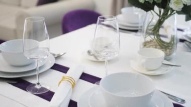 Dining table with kitchen decorations in renovated luxurious property. Table served with white tablecloth and dinnerware in house