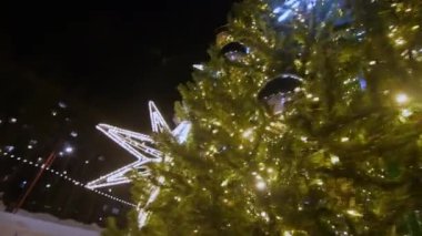 Parlak peri ışıkları ve gece parkına yerleştirilen Noel ağacına takılan büyük mücevherler. Yeni yıl kutlaması