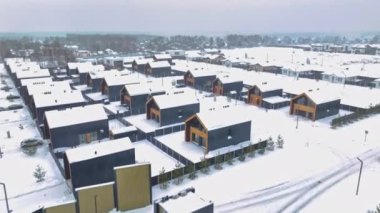 Contemporary cottage buildings with snowy roofs on small town street aerial view. Dwelling suburban district life