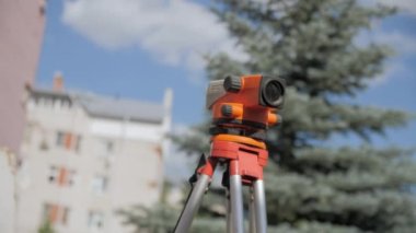Theodolite on tripod against buildings at construction site closeup. Engineer precision optical instrument on street