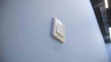 Light switch with white plastic casing on blue wall in office close low angle shot. Button to control lamps in empty room