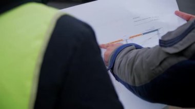 ALMATY, KAZAKHSTAN - 17 FEBRUARY 2023: Taskmaster yol çalışanlara yakın arka görüş planı gösterdi. İşçiler 17 Şubat 'ta Almaty' de banliyöde modern otoyolun çizimleri üzerinde çalışıyorlar.