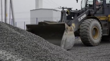 ALMATY, KAZAKHSTAN - FEBRUARY 17 2023: Excavator digs pile of gravel operating at mining quarry closeup. Powerful machine with scoop takes rocks in pit on February 17 in Almaty