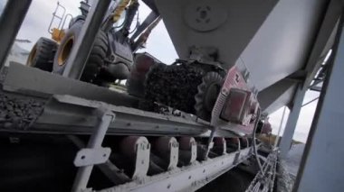 Pouring granite grains from funnel on conveyor belt at rock mining pit closeup. Mineral sources crushing technology