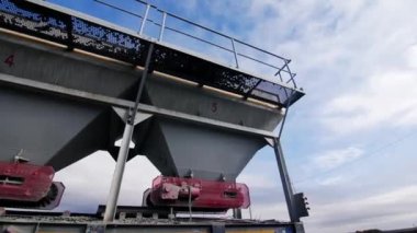 Rock crushing system with huge funnels and conveyor belt in mining quarry. Powerful equipment in gravel pit on sunny day