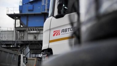 ALMATY, KAZAKHSTAN - FEBRUARY 17 2023: Truck cabin with company logo stands against crushing tower at gravel pit closeup. Branded truck for cargo transportation on February 17 in Almaty