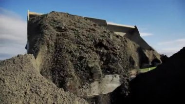 Excavator loads soil into dump truck workbody with large bucket on sunny day closeup. Machinery at construction site