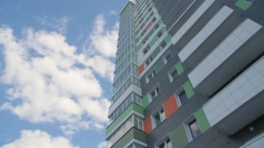 Gökyüzünün altındaki modern apartmanın renkli cephesi. Düşük açılı hafif bulutlar. Kentsel mimari tarzı
