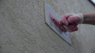 Worker applies textures stucco with putty on wall in renovated building closeup. Interior decoration with modern materials