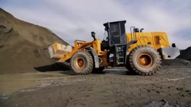 ALMATY, KAZAKHSTAN - SEPTEMBER 08 2022: Backhoe, toprak tepeyi kepçeyle kazıyor ve maden ocağında kaya ezme sistemine karşı geriye doğru gidiyor. Eylül 08 'de Almaty' de taş ocağı makineleri çalışıyor.