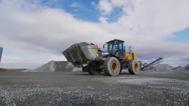 ALMATY, KAZAKHSTAN - Eylül 08 2022: Kazıcı maden ocağı kapanışı boyunca kova içinde granit taneleri taşır. Eylül 08 'de Almaty' de kaya yatağı çıkarma makineleri