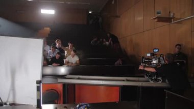 ALMATY, KAZAKHSTAN - 15 Ağustos 2022: Üniversite sınıfında kağıt fırlatan aktörlerin çekim ekibi. Kameraman 15 Ağustos 'ta Almaty' de gençlik hakkında çekilecek film için aktörler