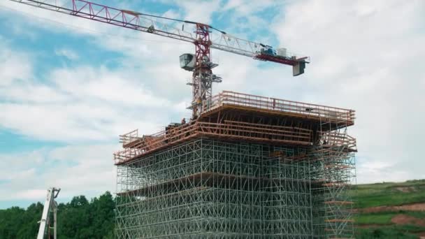 Baustelle Mit Funktionierendem Turmdrehkran Und Unfertiger Brückenstütze Zwischen Stahlbeschlägen Gegen — Stockvideo