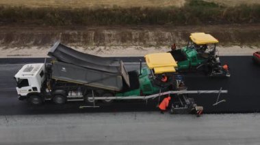 ALMATY, KAZAKHSTAN - 17 Şubat 2023 Müteahhitler asfalt kaldırım makinesini kırsal otoyol manzarasına göre ayarlıyorlar. 17 Şubat 'ta Almaty' de otoyol bakım sahasının çağdaş makineleri