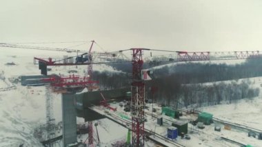 ALMATY, KAZAKHSTAN - 17 Şubat 2023: Kış günü havadan bakıldığında kırsal bölgede tamamlanmamış ulaşım köprüsü yakınlarında yüksek kule vinçleri. Altyapı geliştirmesi 17 Şubat 'ta Almaty' de