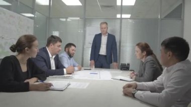 ALMATY, KAZAKHSTAN - 17 Şubat 2023: Patron ofiste yapılan toplantı sırasında iş geliştirme için takım fikirlerini dinliyor. Müdür, 17 Şubat 'ta Almaty' de şirket personeliyle beyin fırtınası yapıyor.
