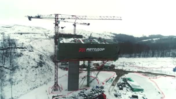 2023年2月17日 雪上谷の空中風景の中で将来の自動車陸橋区間とタワークレーン アルマトイの2月17日建設現場における近代的な建築技術 — ストック動画
