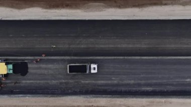 Çöp kamyonu ve asfalt kaldırım taşıtları. İnşaatçılarla birlikte otoyolun üst manzarasında. Yol çalışması geliştirme mekanizması