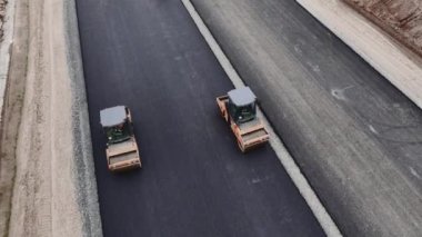 Paten kamyonları, yol şeridi hava sahasında asfalta basıyor. Çağdaş makinelerle otoyol inşa süreci