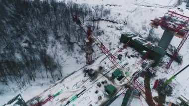 Karlı, içi boş, üst manzaralı otoyol inşaatındaki köprü bölümünün üstüne vinç çek. Kış manzarası ve teknoloji