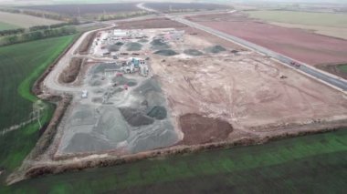 Büyük açık taş ocağı, taşra manzaralı, bakımlı yol kenarında, makineler ve çakıl yığınları ile. İnşaat alanı ile manzara