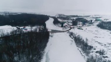 Donmuş nehir ve tamamlanmamış ulaşım yolu üstgeçitlerinin destek kolonları kış ormanı hava manzarası. Kırsal kalkınma süreci