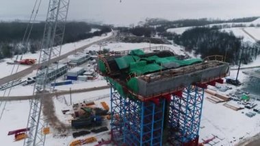 Köprü, metal gövde ve kışın vadi havası manzaralı toprak desteğiyle destekleniyor. Yol yapım makineleri ile kırsal alan