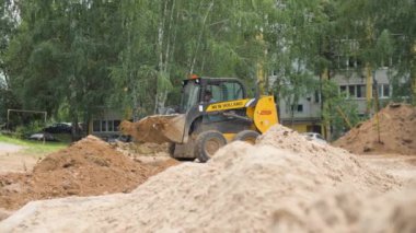 ALMATY, KAZAKHSTAN - Haziran 06 2022: Kazıcı inşaat için kum temizleme şantiyesini boşaltıyor. Kepçeli buldozer yazın kum yığınının üzerine dökülür.