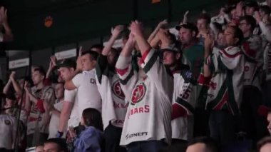 ALMATY, KAZAKHSTAN - 27 Mart 2023: Hokey maçında favori oyuncular için takım logosu giyen hevesli hayranlar tezahürat yapıyor. İzleyiciler oyuncuları desteklemek için el çırpıyor