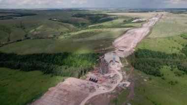 İnşaat alanındaki boş hava manzaralı bina iskelesi ve takviyeyle eksik köprü desteği. Otoyol inşa teknolojisi