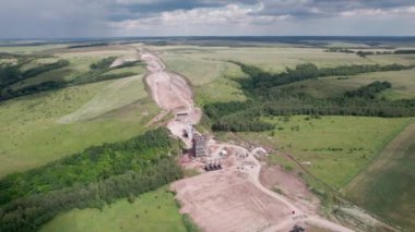 Boş alan hava manzarasında inşaat alanında iskeleleri olan bir nakliye köprüsü desteği. Ormanlı, peyzajlı bir yerde inşaat