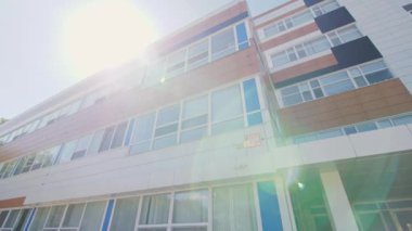 Ön cephede pencereleri olan ofis binası ve alçak açılı, parlak güneş ışığı altında giriş verandası. Kamu ihtiyaçları için şehir mimarisi